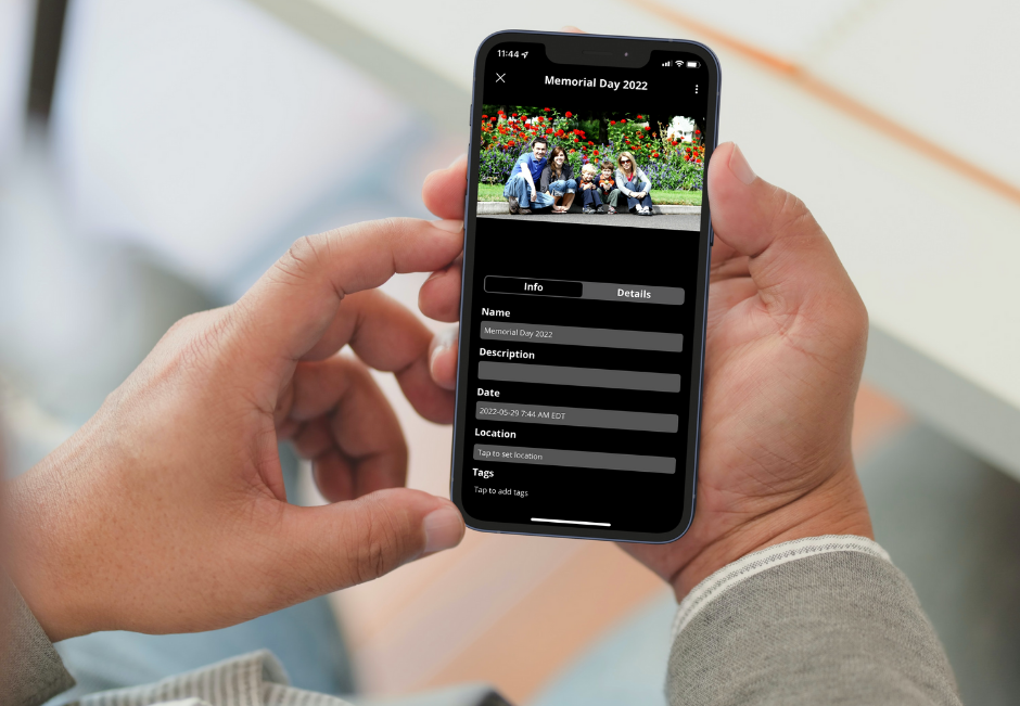 A pair of hands holding a phone displaying a family photo titled "Memorial Day 2022"