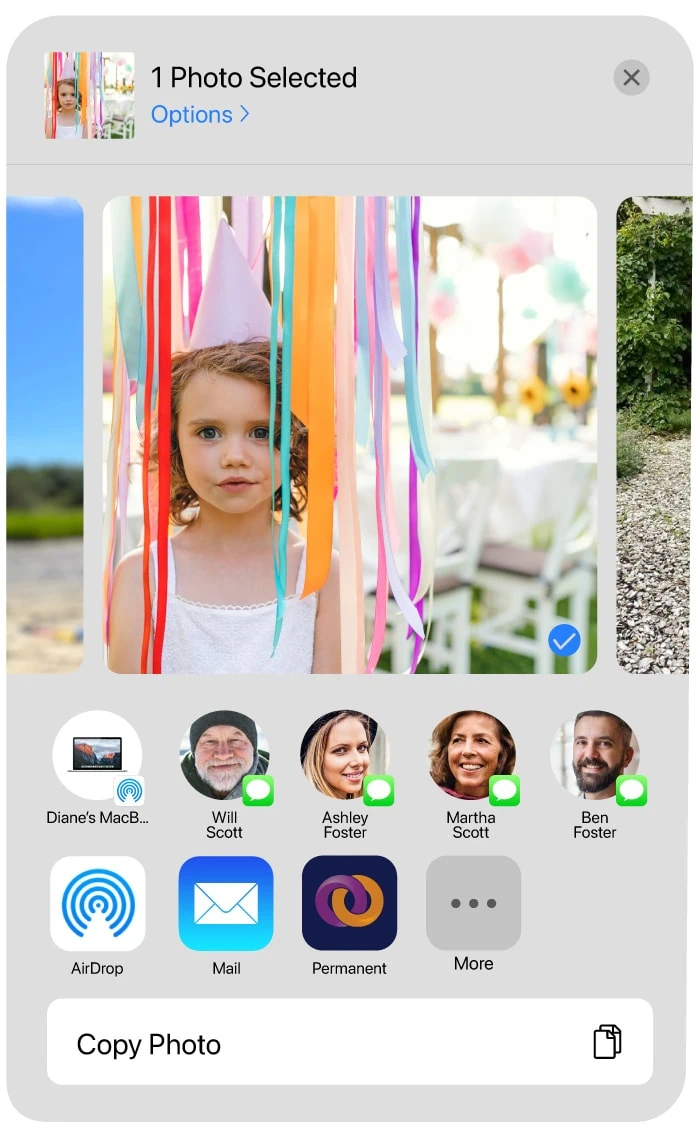 A photo of a girl wearing a party hat standing among colorful streamers selected in a mobile interface. Below the photo, a list of apps through which it could be shared, including the Permanent app